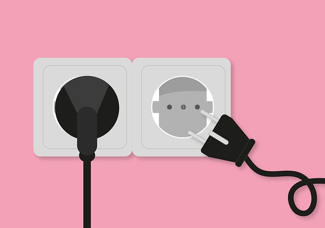 A charger going into a plug on the wall.